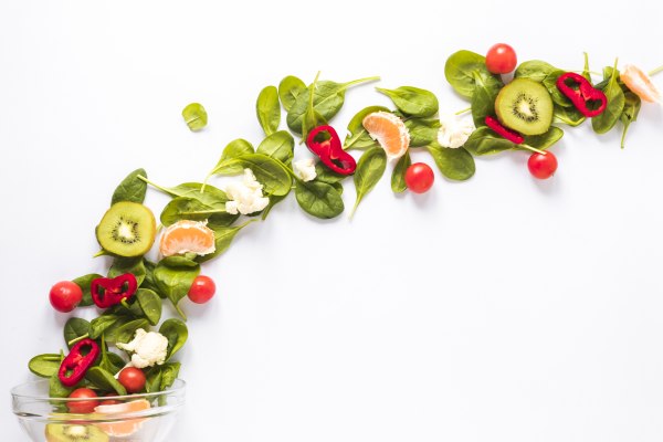 owoce i warzywa pokrojone na sałatkę rozrzucone na białym tle